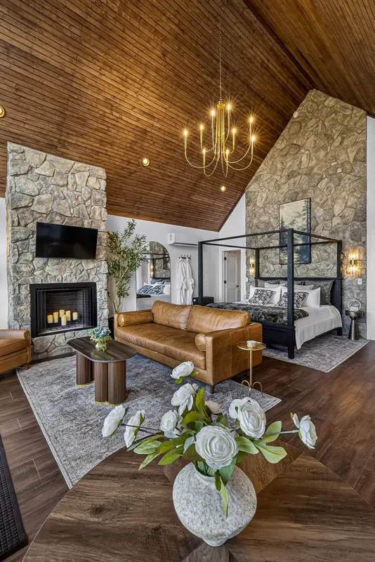 The stone hearth rising to the vaulted wood ceiling