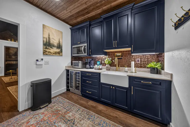 The kitchenette with navy cabinetry, farmhouse sink and wine refrigerator