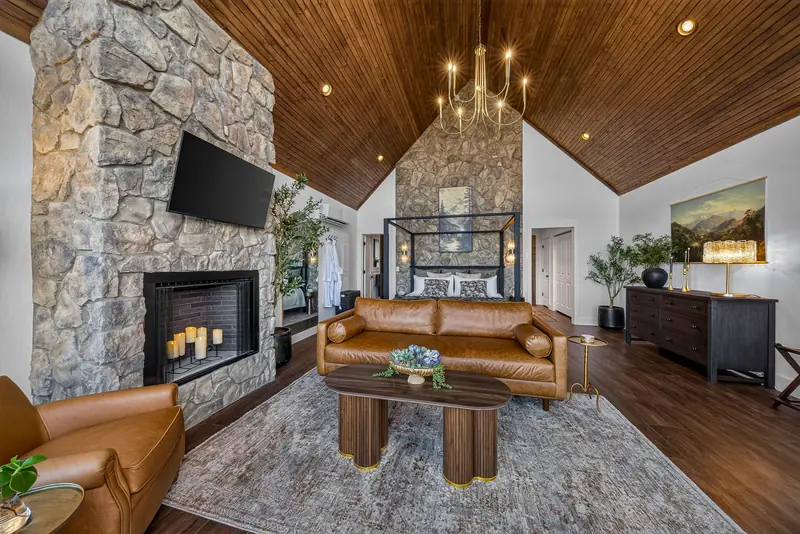 Leather seating gathered around the floor-to-ceiling stone fireplace