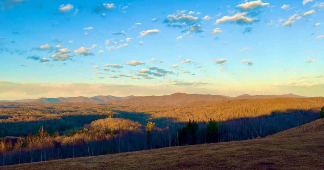 Panoramic mountain vista at golden hour with rolling ridgelines and dramatic sky