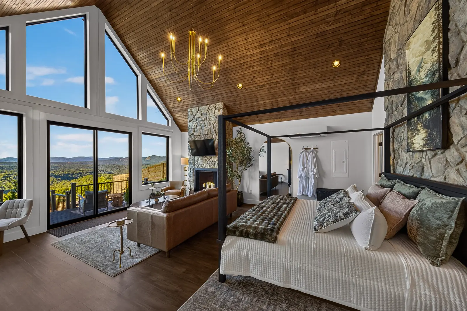 A four-poster canopy bed dressed in white linens beneath the A-frame windows